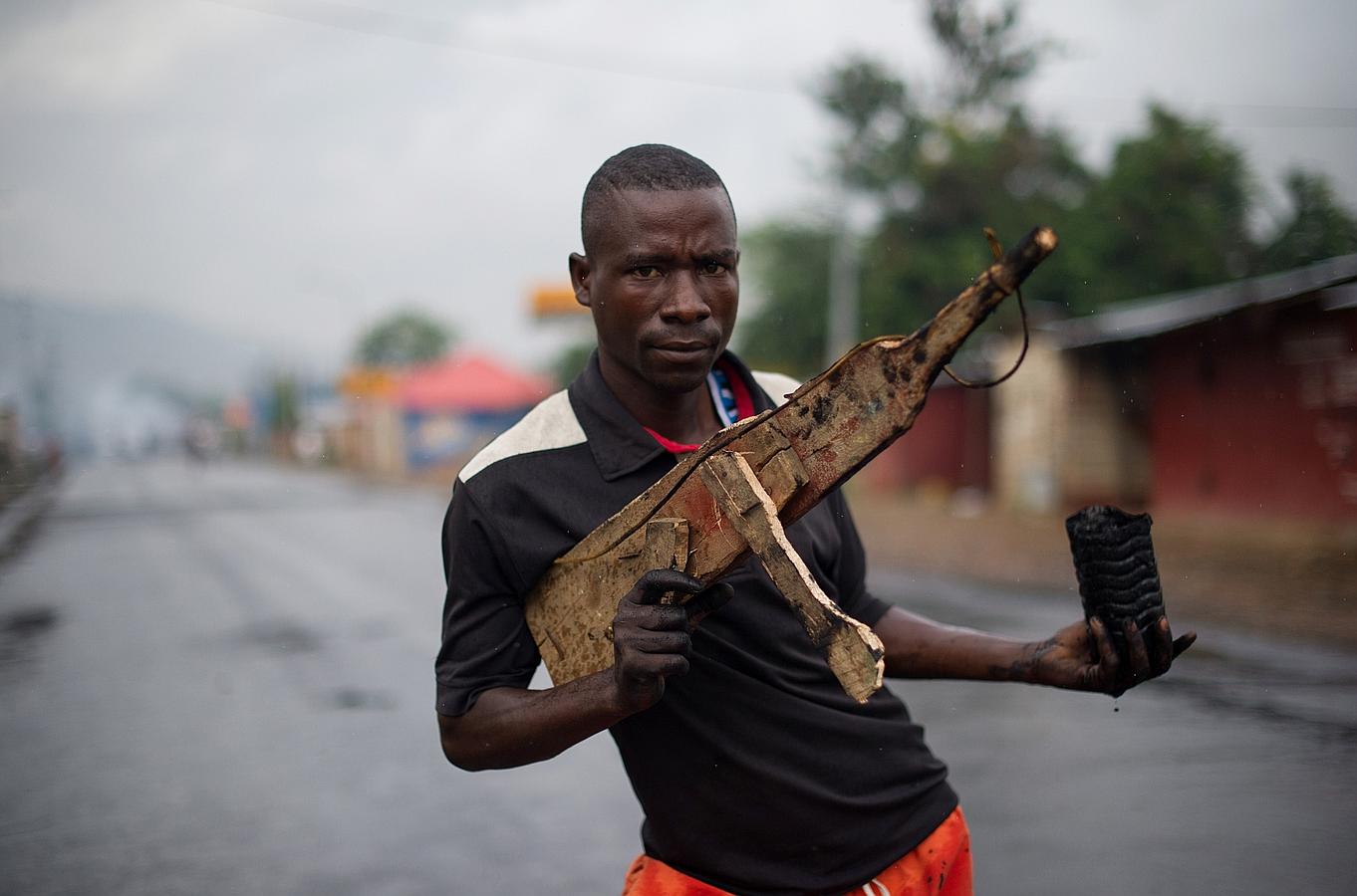 Un hombre posa con un rifle de madera en el barrio Musaga en Bujumbura, Burundi.