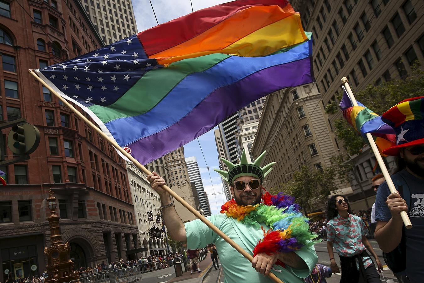 Un hombre vestido como la Estatua de la Libertad lleva una bandera de Estados Unidos Rianbow mientras marcha en un desfile del orgullo gay en San Francisco, California.