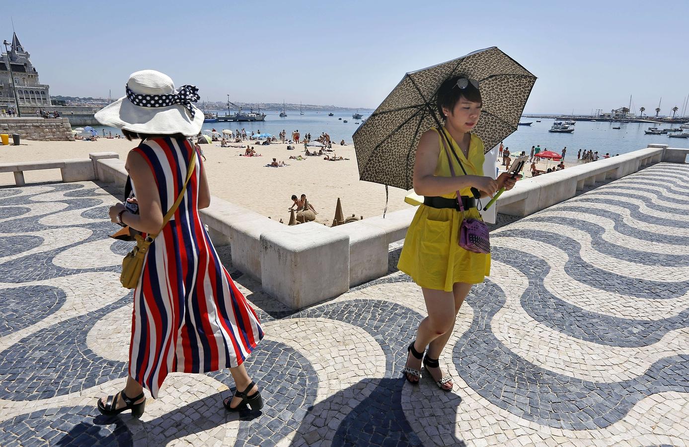 Una turista utiliza un paraguas para protegerse del sol durante un paseo por la playa de Cascais en las afueras de Lisboa el 29 de junio de 2015.