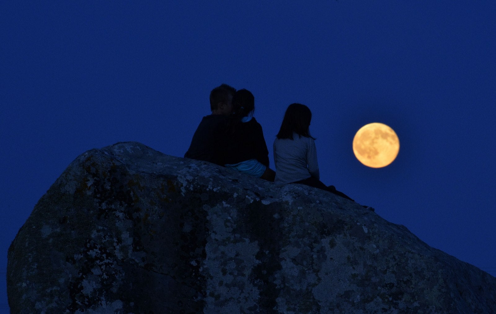 Niños ven la luna llena sobre el menhires de Sainte-Barbe en Plouharnel, Bretaña.