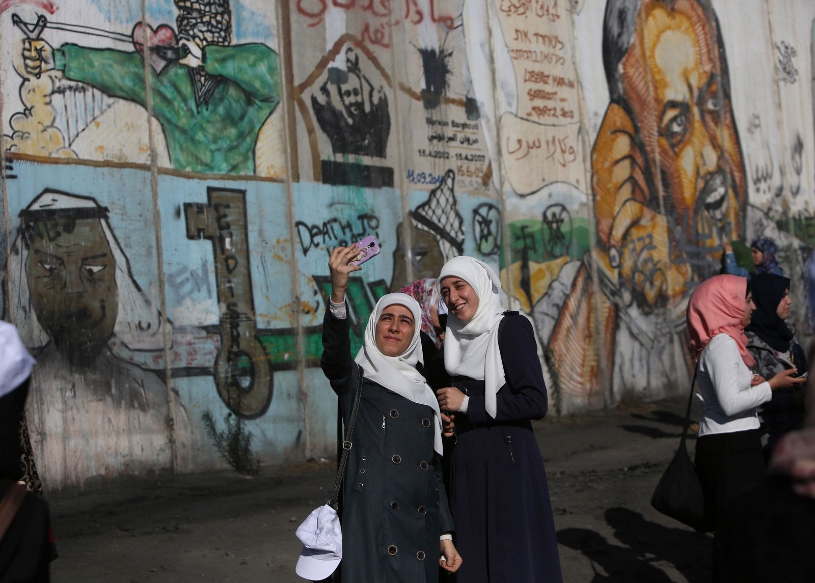 Mujeres palestinas toman un selfie cerca de una sección del muro de separación de Israel en Qalandia puesto de control entre Ramallah y Jerusalé.