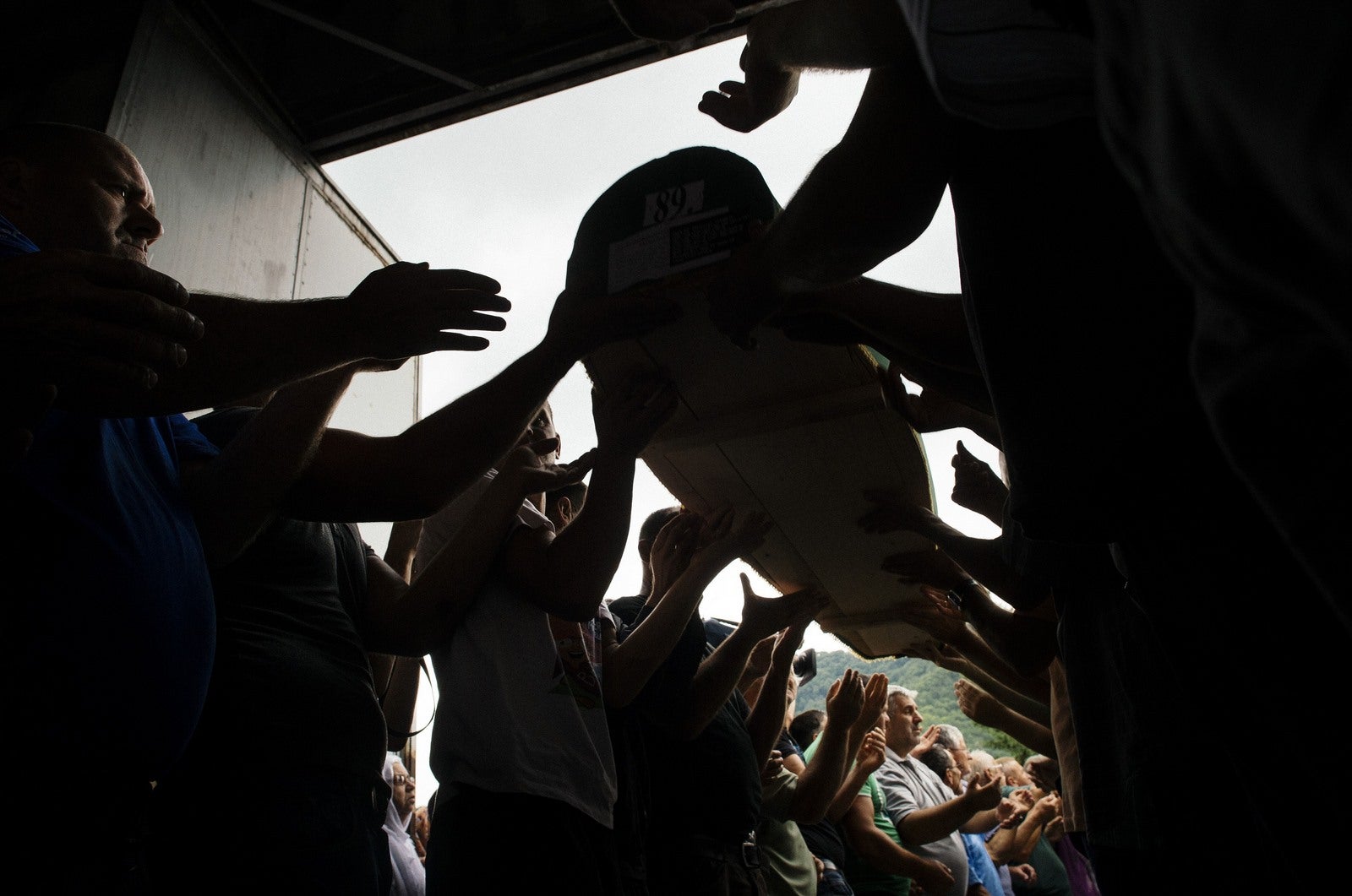 Hombres bosnios llevan uno de los ataúdes con los restos de 136 víctimas recientemente identificadas de la masacre de Srebrenica en 1995 recién llegado a la antigua fábrica de baterías en Potocari, cerca de la ciudad de Bosnia oriental de Srebrenica.