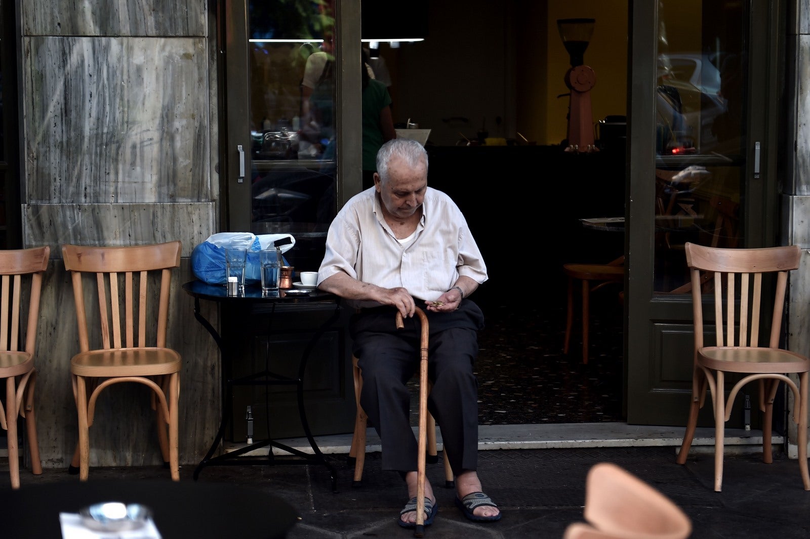 Un anciano se sienta en un café en el centro de Atenas .