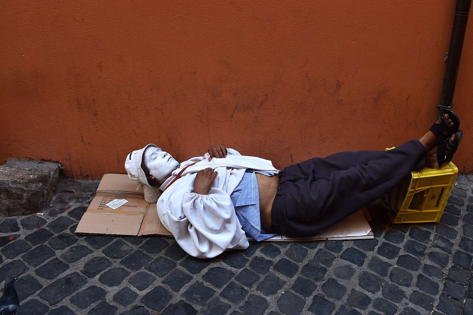 Un artista callejero se echa siesta a la sombra en una pequeña calle en el centro.