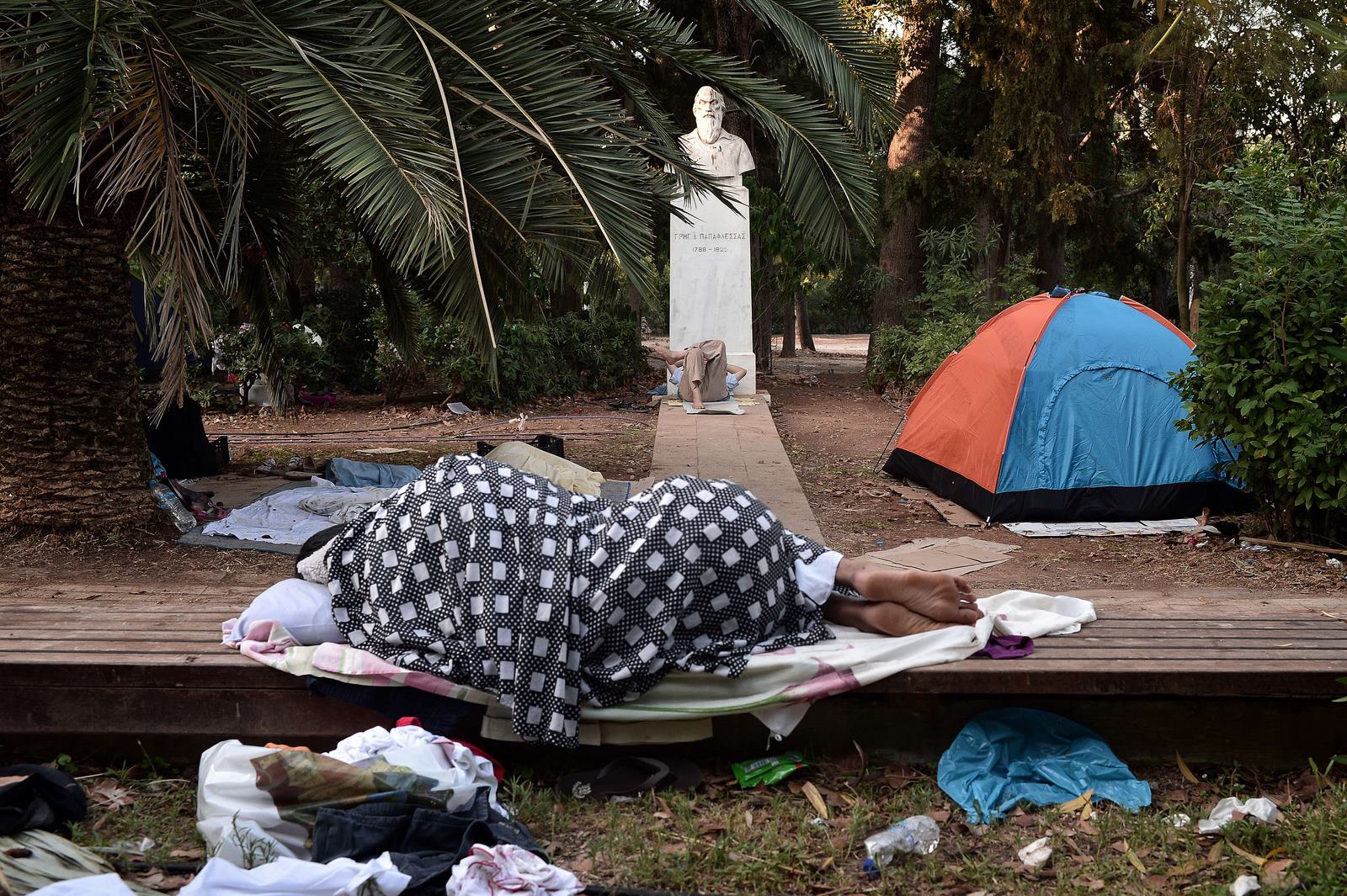 Inmigrantes duermen en un parque en el centro de Atenas, donde encontraron un refugio temporal después de llegar de las islas griegas.