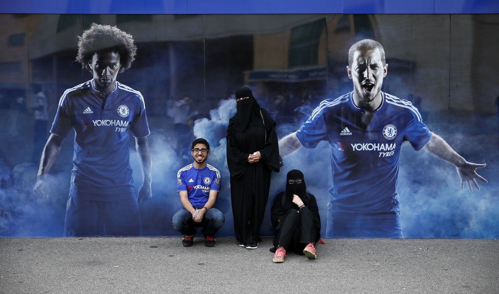 Seguidores del Chelsea posan para una fotografía junto a un gran cartel del equipo.