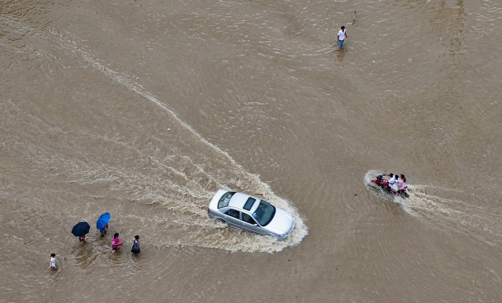 Vehículos y residentes circulan por una calle inundada en Wenling, después de las fuertes tormentas del Tifon Soudelor.