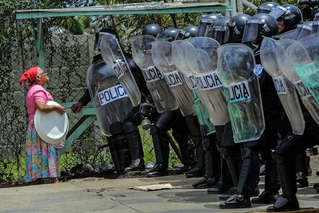 Una mujer habla con policías antidisturbios para ir a la su casa durante una protesta contra el sistema electoral en Managua.