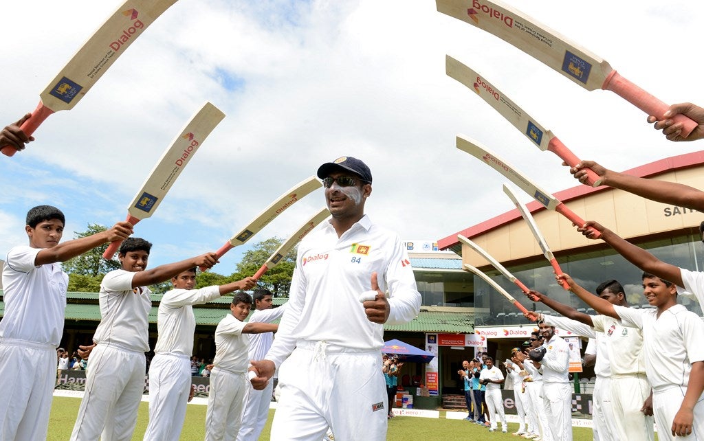 El jugador de cricket de Sri Lanka Kumar Sangakkara (C) camina a través de un "arco de bates de cricket", al  salir al campo durante el día de la inauguración de su segundo test match entre Sri Lanka y la India en el Estadio de Cricket P. Sara Oval en Colombo .