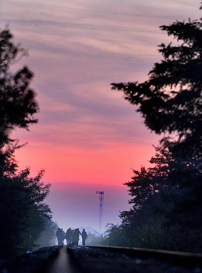 Inmigrantes caminan por las Vías del tren que une Serbia y Hungría, cerca de Röszke, a 180 km al sur de Budapest, Hungría, al amanecer.