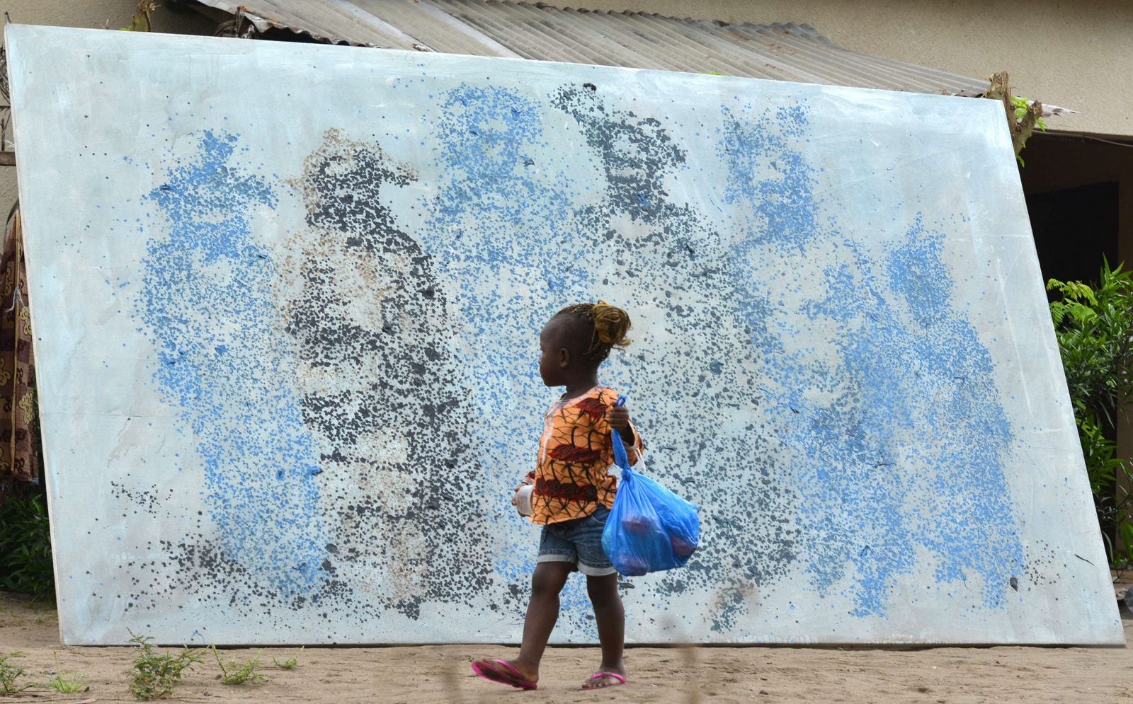 Un niño pasa junto a una pintura del artista de Costa de Marfil Lanín Saint-Etienne Yeanzi.