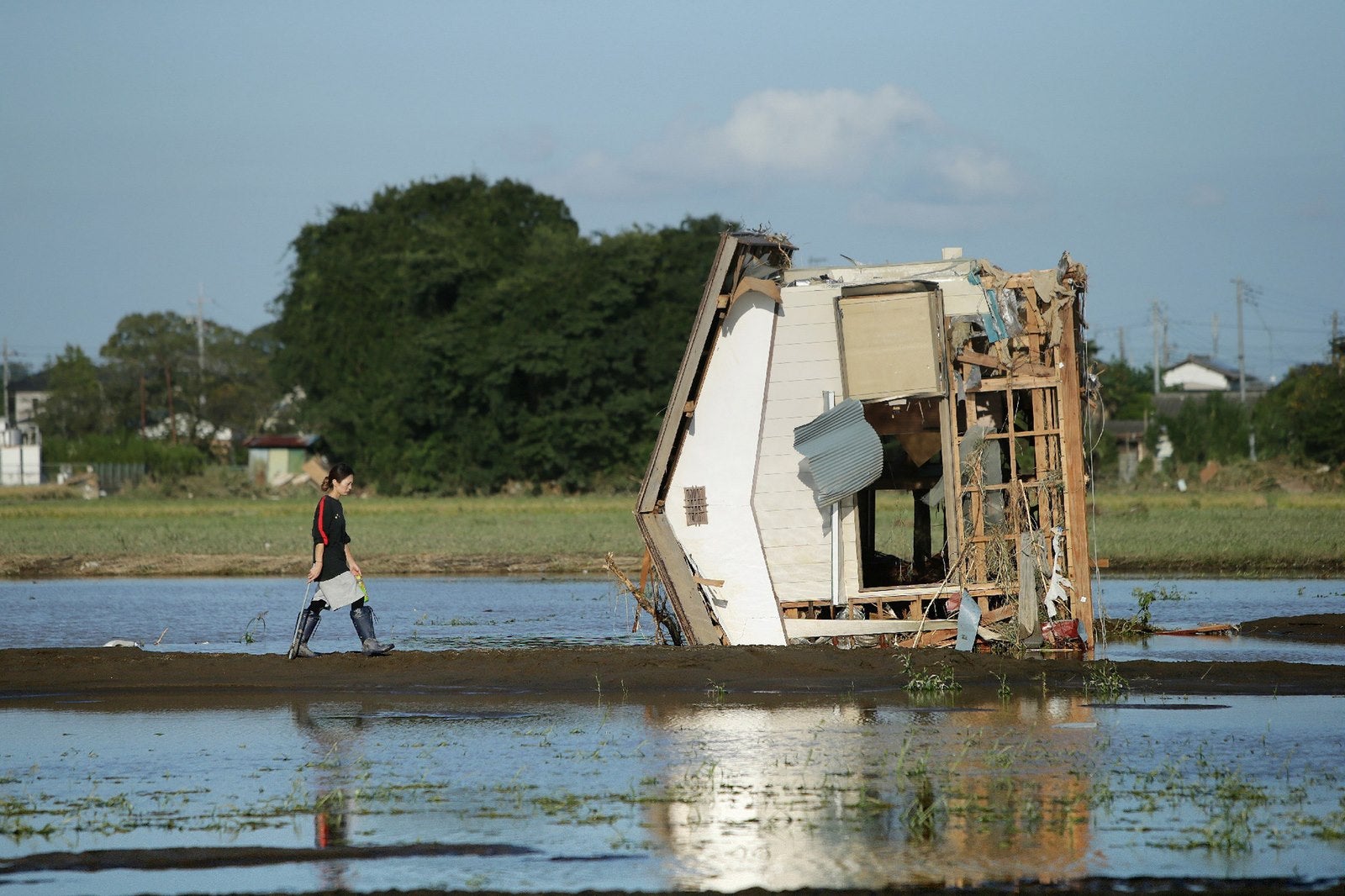 Una mujer camina hacia una casa derrumbada en un campo inundado por las aguas en Joso en la prefectura de Ibaraki.