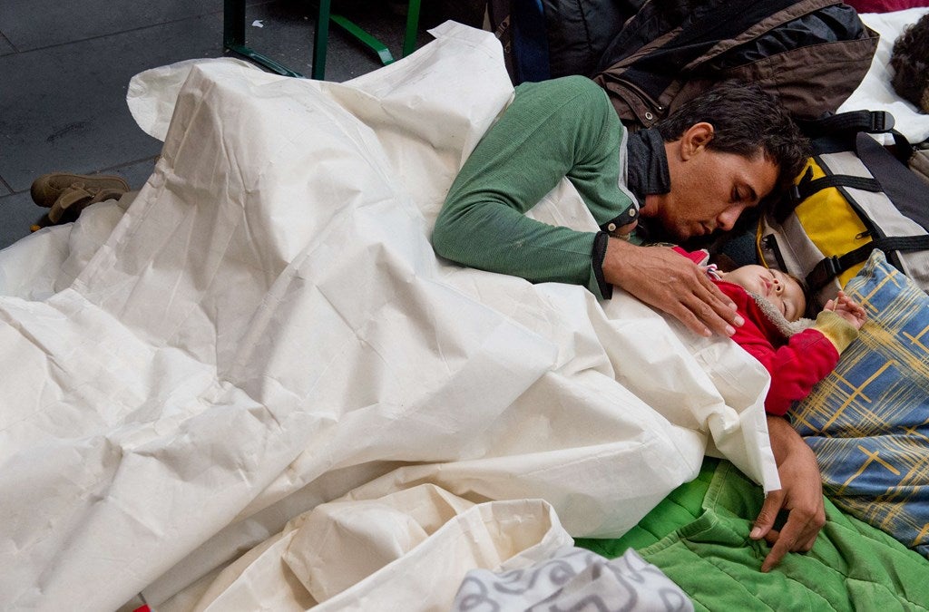 Un hombre y un niño duerma en la estación de tren principal de Frankfurt am Main, Alemania occidental, donde los refugiados de Siria, Irak y Pakistán llegaron durante la noche con un tren procedente de Austria.