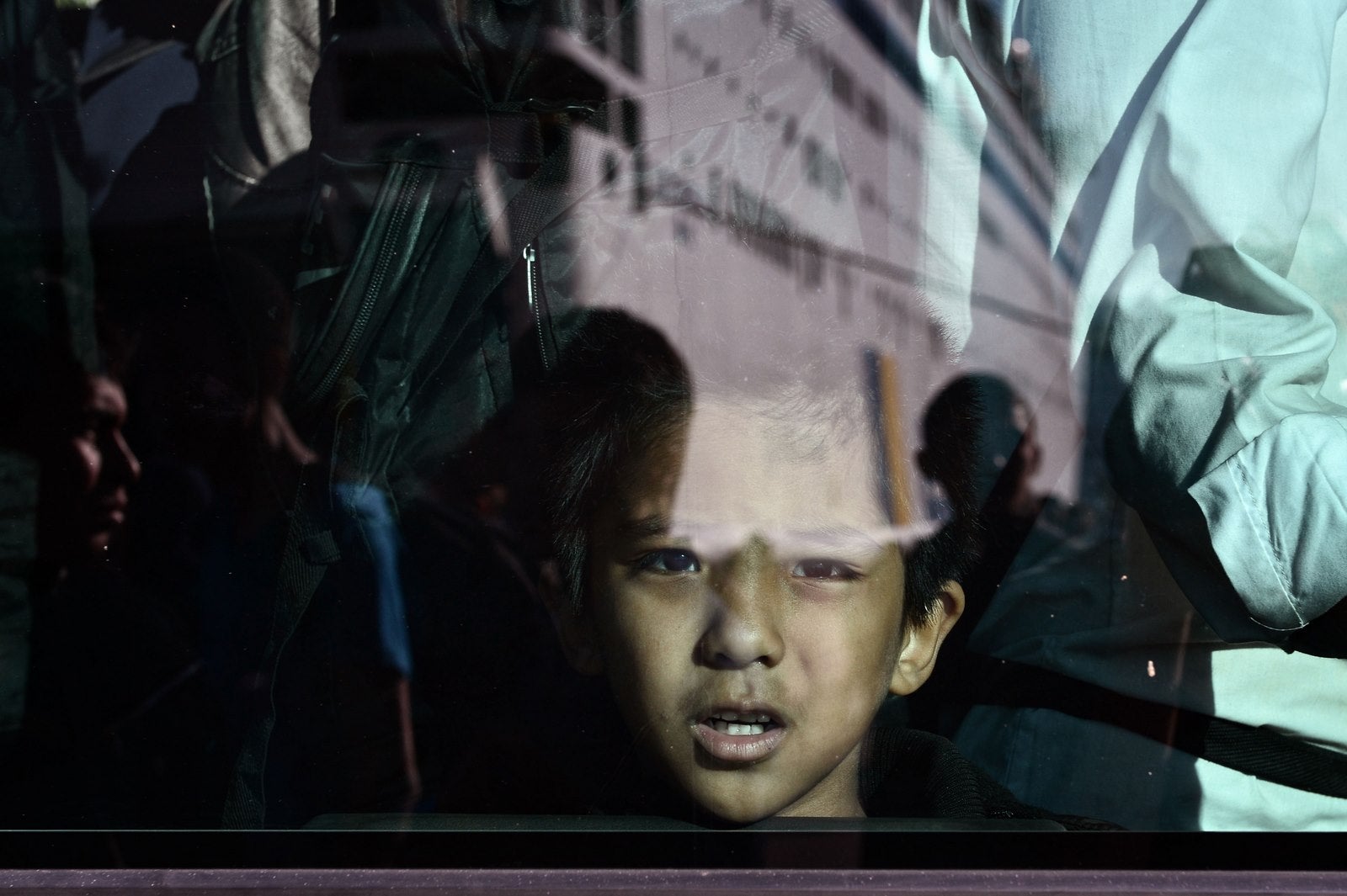 Un niño refugiado mira fuera de una ventana del autobús, después de desembarcar en el puerto de El Pireo.