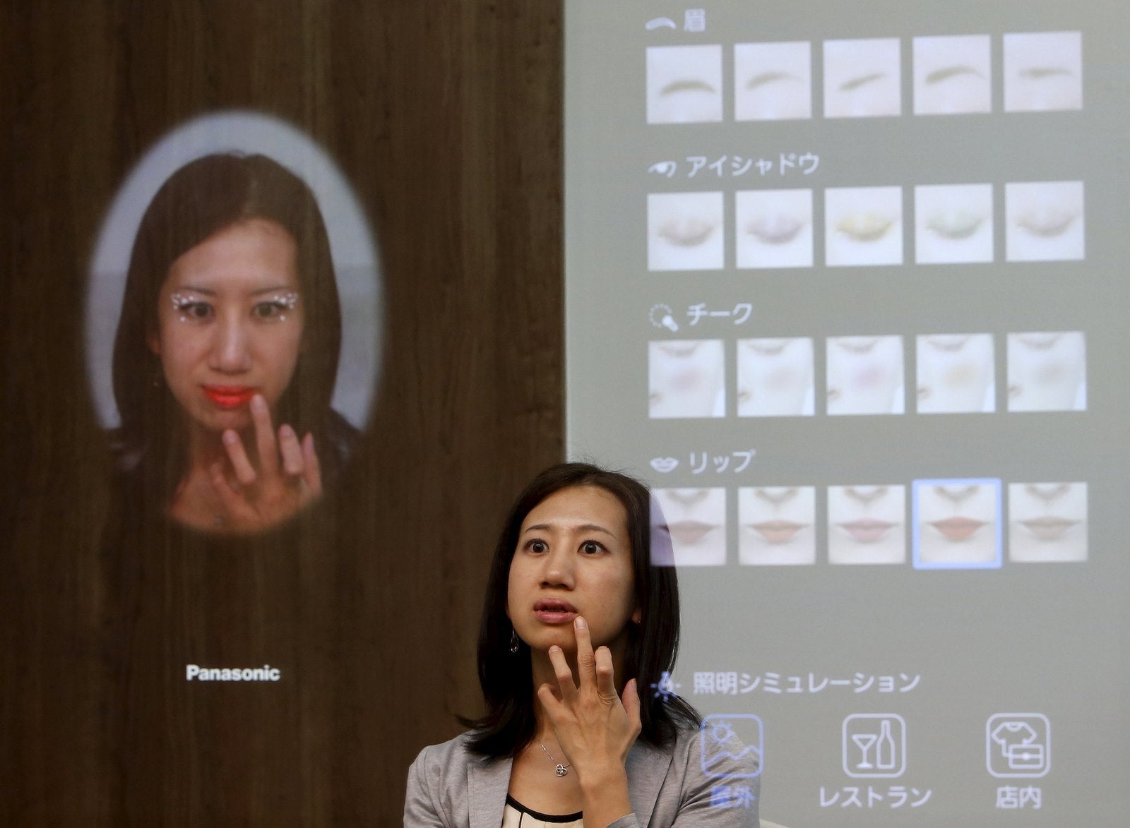 Una mujer se refleja en el espejo interactivo de Panasonic Corp, que es capaz de aplicar el maquillaje virtual y detectar enfermedades de la piel.