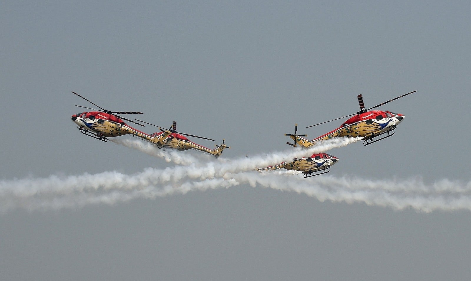 Helicópteros del equipo de acrobacias aéreas Sarang de la Fuerza Aérea de la India realizan durante plena ensayo general para el desfile del Día de la Fuerza Aérea en Nueva Delhi.