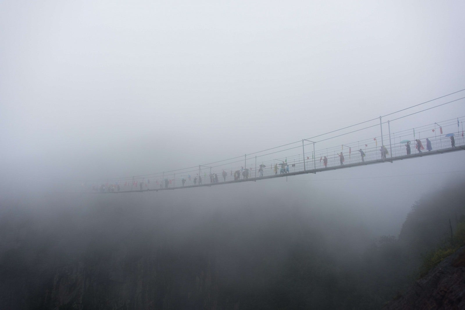 Turistas chinos a pie a través de un puente colgante con fondo de cristal en las montañas en el condado de Pingjang Shinuizhai, provincia de Hunan, a unos 150 kilómetros de Changsha.