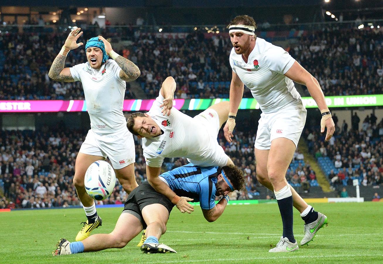 Alex Goode (C) es abordado durante el partido del Grupo A de la Copa Mundial de Rugby 2015 entre Inglaterra y Uruguay en el estadio de la ciudad de Manchester, noroeste de Inglaterra.