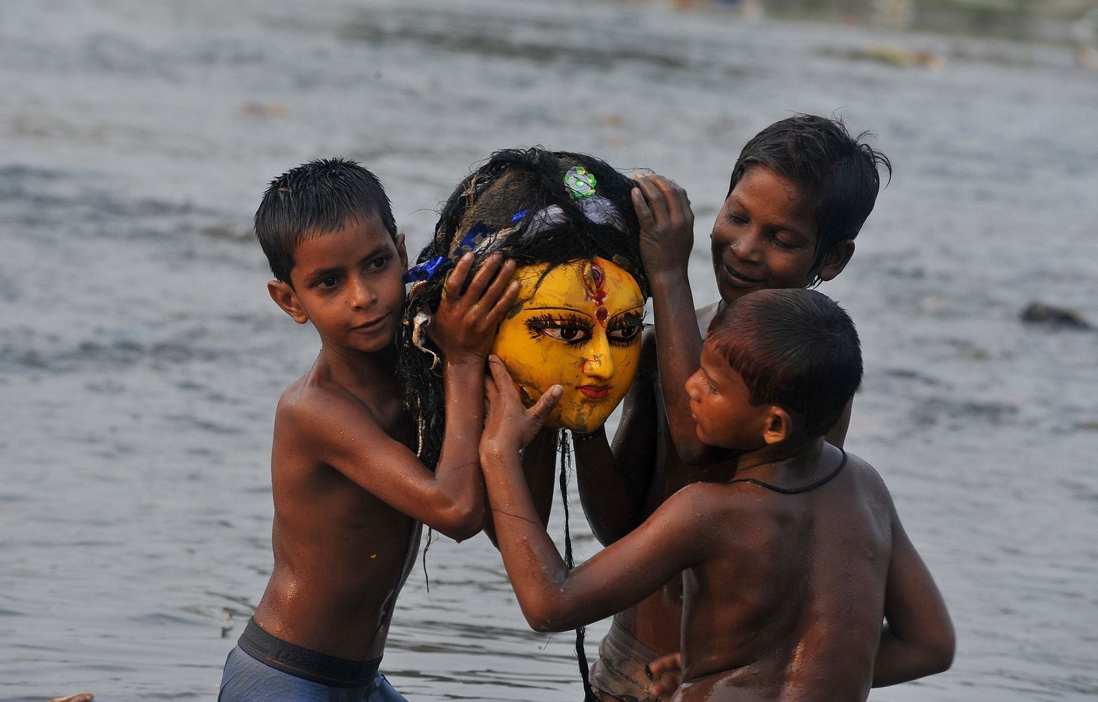 Muchachos indios llevan la cabeza de barro de la diosa Durga después de haber sido sumergido por los devotos hindúes en el río Mahananda en Siliguri en Ocotber.