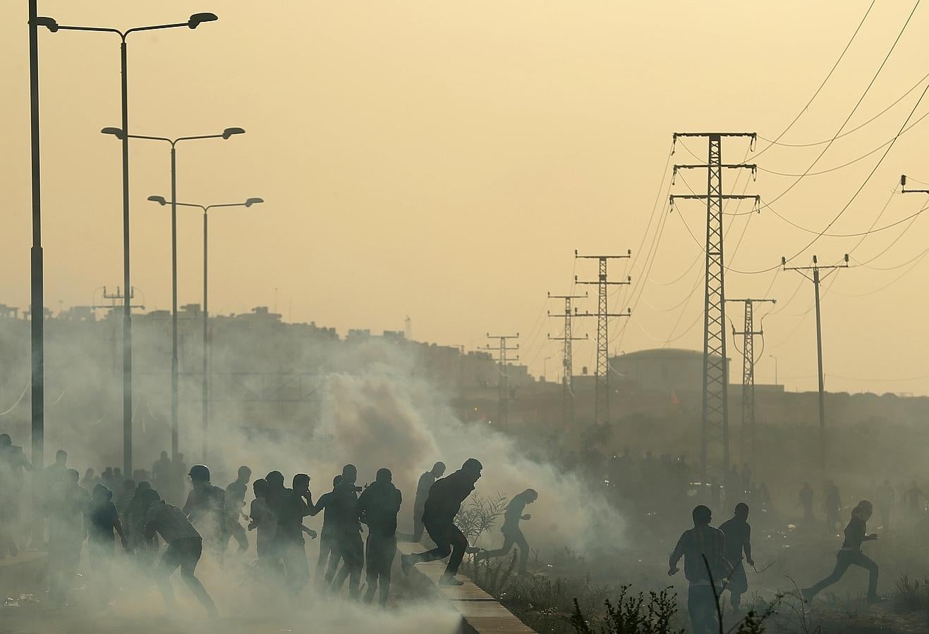 Manifestantes palestinos corren a esconderse de gas lacrimógeno durante los enfrentamientos con las fuerzas de seguridad israelíes cerca de la frontera con Israel en el cruce de Erez en la franja norte de Gaza .