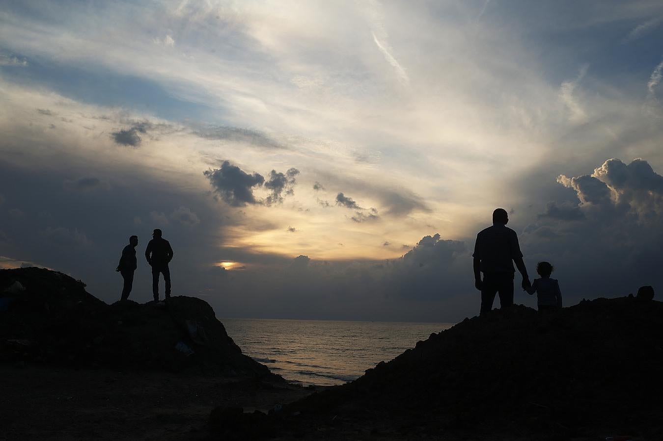 Palestinos en una playa durante la puesta de sol sobre la ciudad de Gaza.