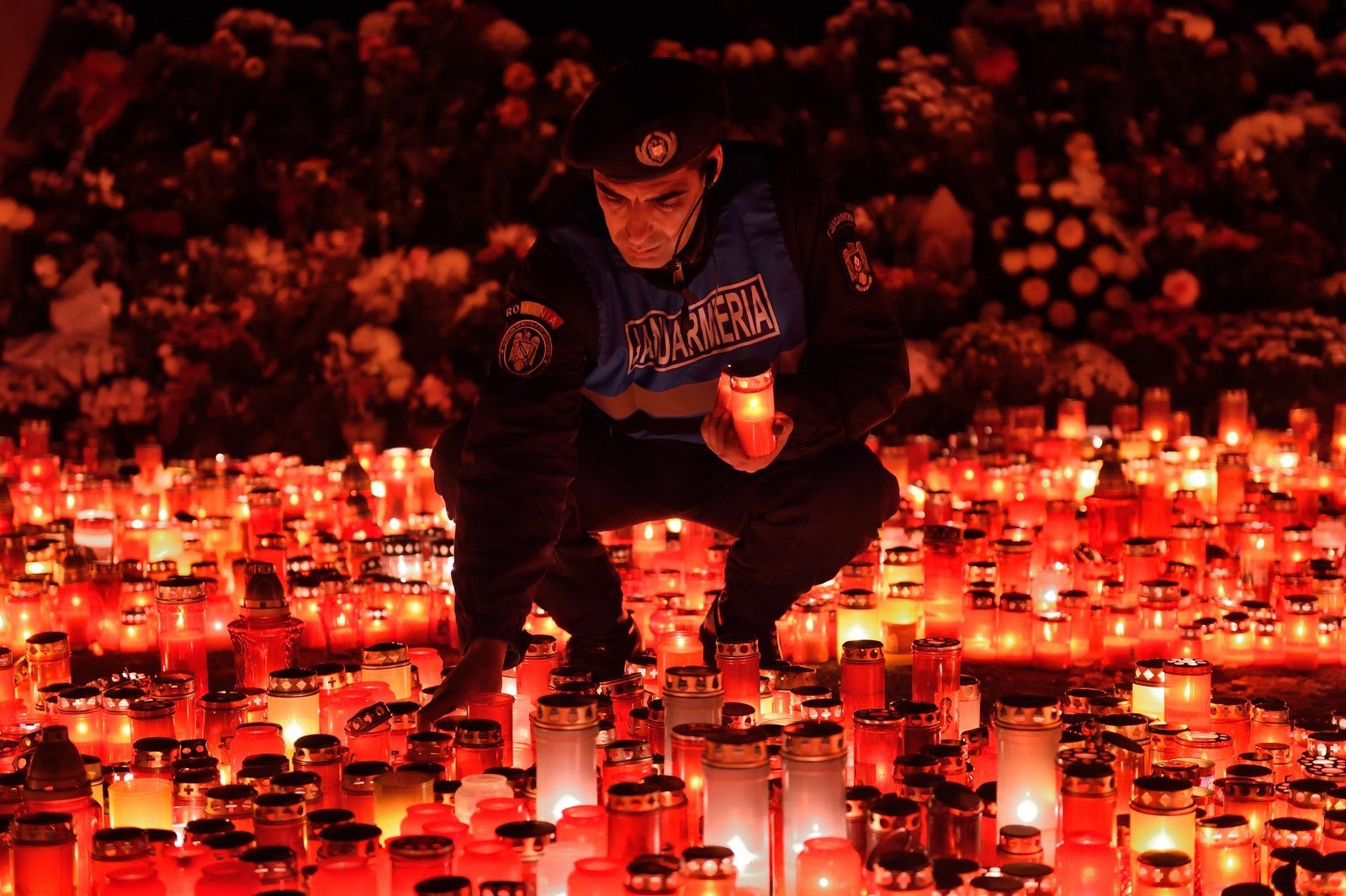 Un gendarme rumano coloca velas dadas por las personas que vinieron a rendir homenaje a las víctimas del incendio en la discoteca "colectiv" en Bucarest.