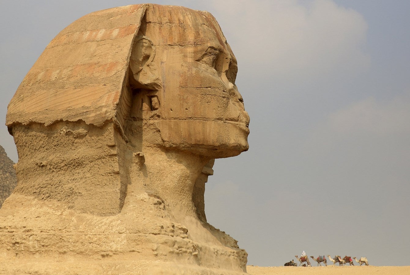 Un trabajador monta su camello mientras espera a los turistas delante de la Esfinge en las pirámides de Giza, en las afueras de El Cairo, Egipto.