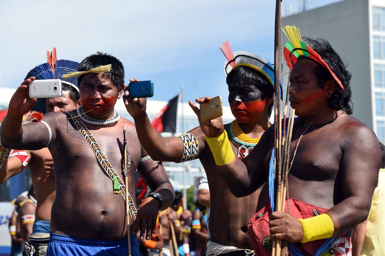 Nativos de las etnias Kayapo y Pataxó tomar instantáneas con sus teléfonos móviles durante una protesta frente al Congreso mientras que  los legisladores discuten la ley que modifica la demarcación de sus tierras, en Brasilia.
