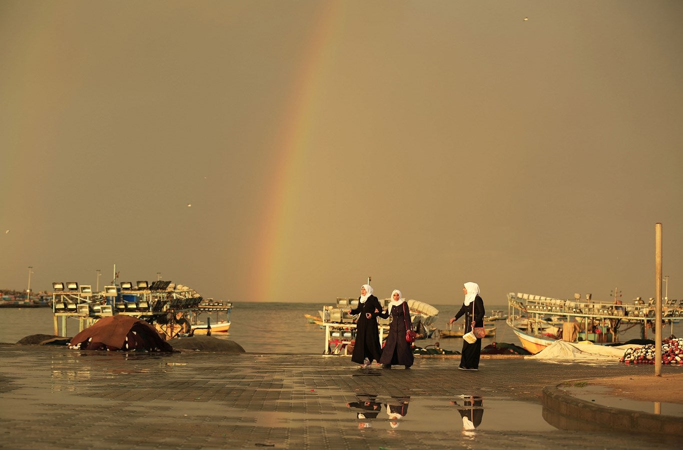 Niñas palestinos caminan delante de un arco iris que ilumina el cielo sobre la ciudad de Gaza.