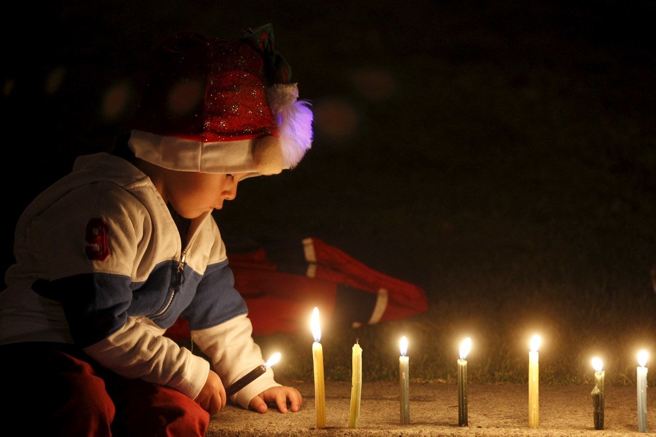 Un niño enciende  velas en el Parque Simón Bolívar de Bogotá  para marcar el inicio de las fiestas de Navidad.