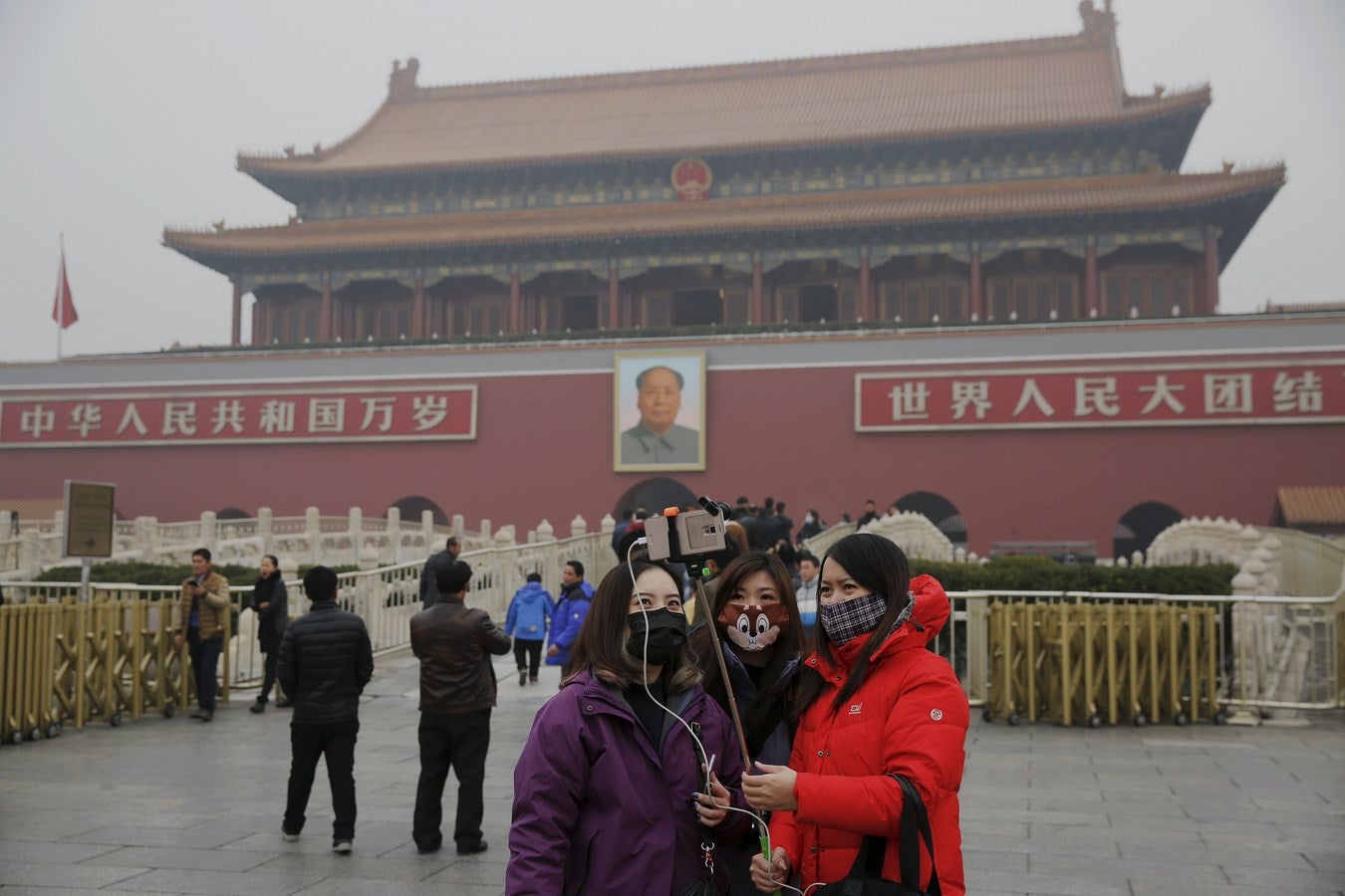 Mujeres con máscaras se protegen de la contaminación extrema mientras se toman fotos en la Puerta de Tiananmen en Pekín. La capital de China emite su primera "alerta roja" por la contaminación.