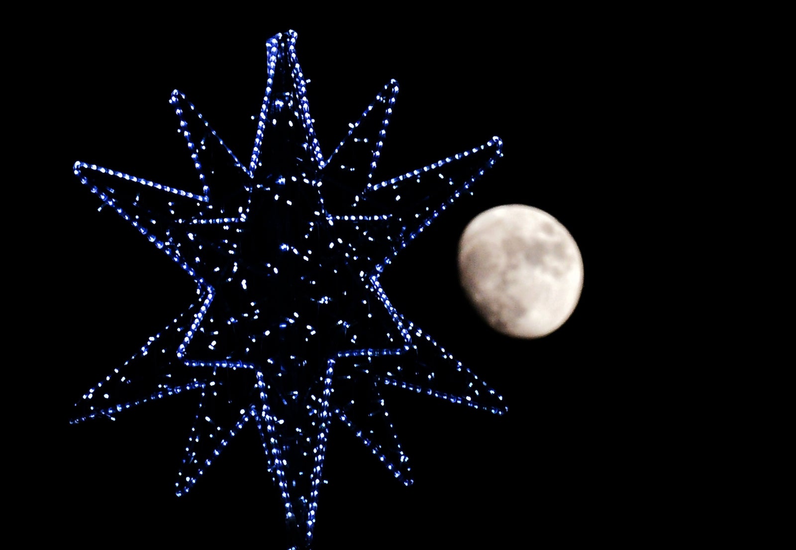 La luna se eleva detrás de la estrella de un árbol de Navidad en el centro de Roma.