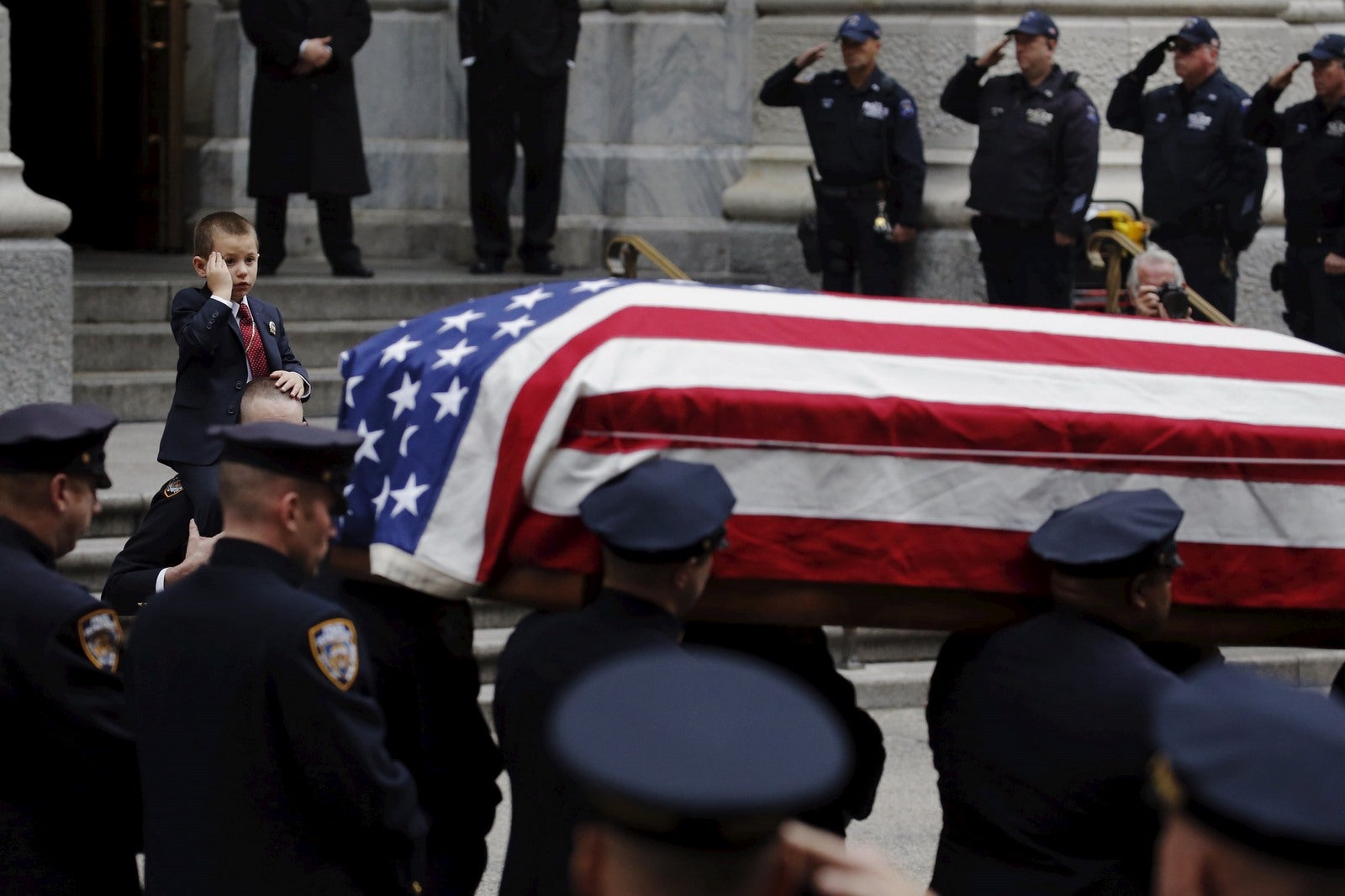 Ryan Lemm, de 4 años, hace gestos mientras observa el ataúd de su padre, oficial de policía de Nueva York José.