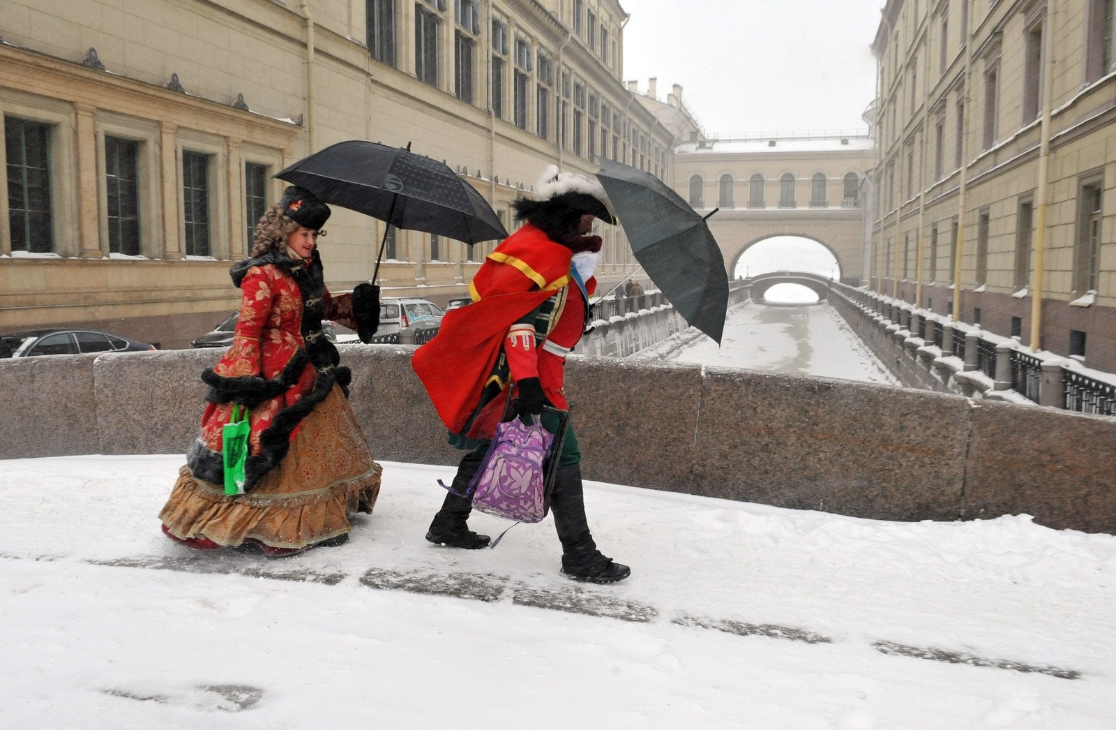 Actores vestidos como el zar Pedro el Grande y la emperatriz Catalina cruzan un puente cubierto de nieve en el centro de San Petersburgo.