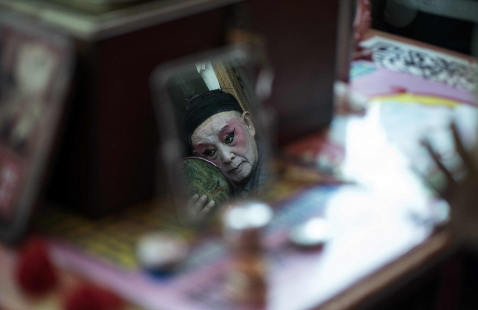 Kunming muestra Él Zhengcai, director de la compañía teatral 'Flower Lantern', que se refleja en un espejo, mientras se pone su maquillaje.