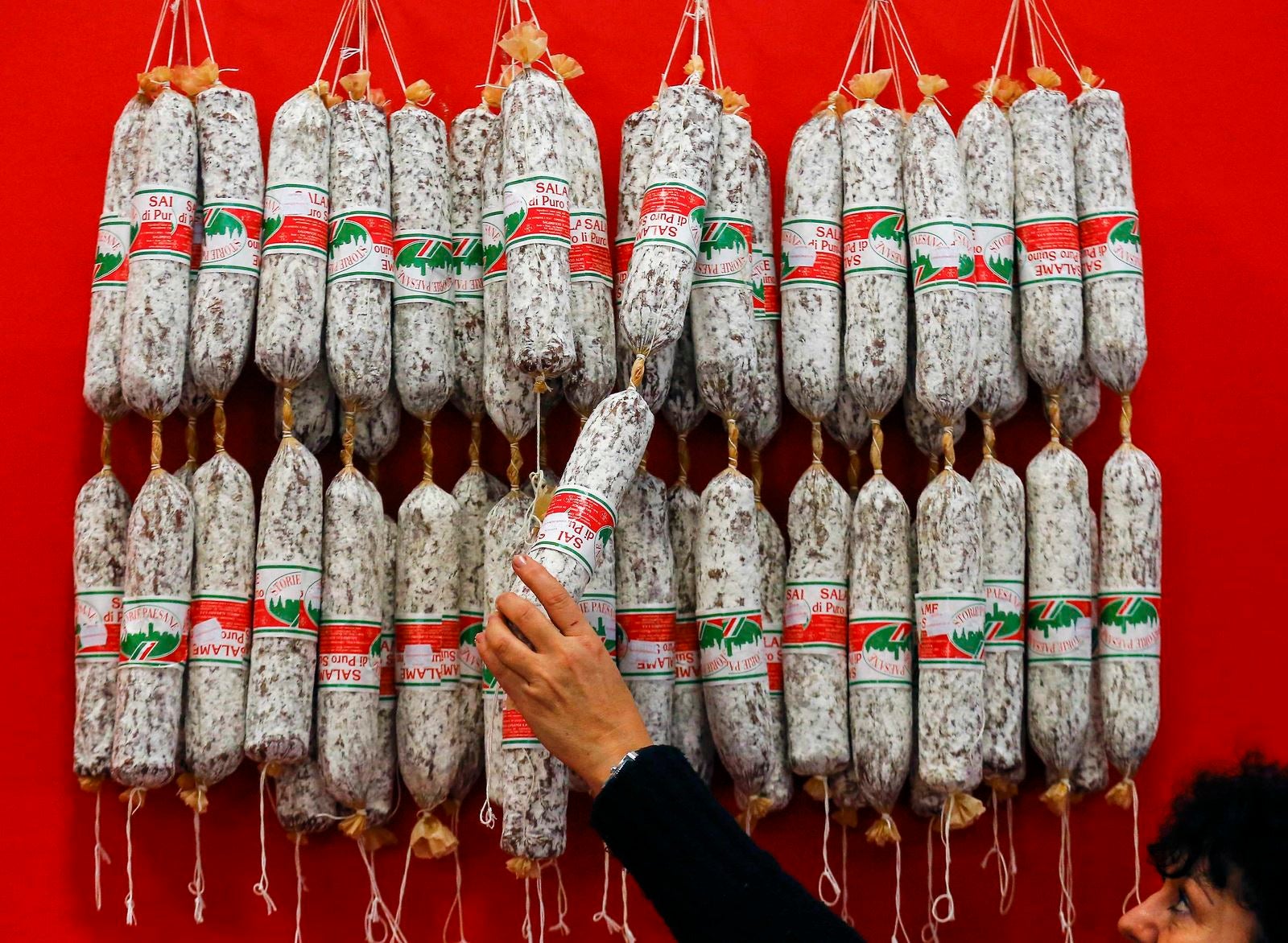 Un expositor italiano cuelga salamis durante los preparativos de la Semana Verde de comida internacional, la agricultura y la horticultura feria de Berlín, Alemania.