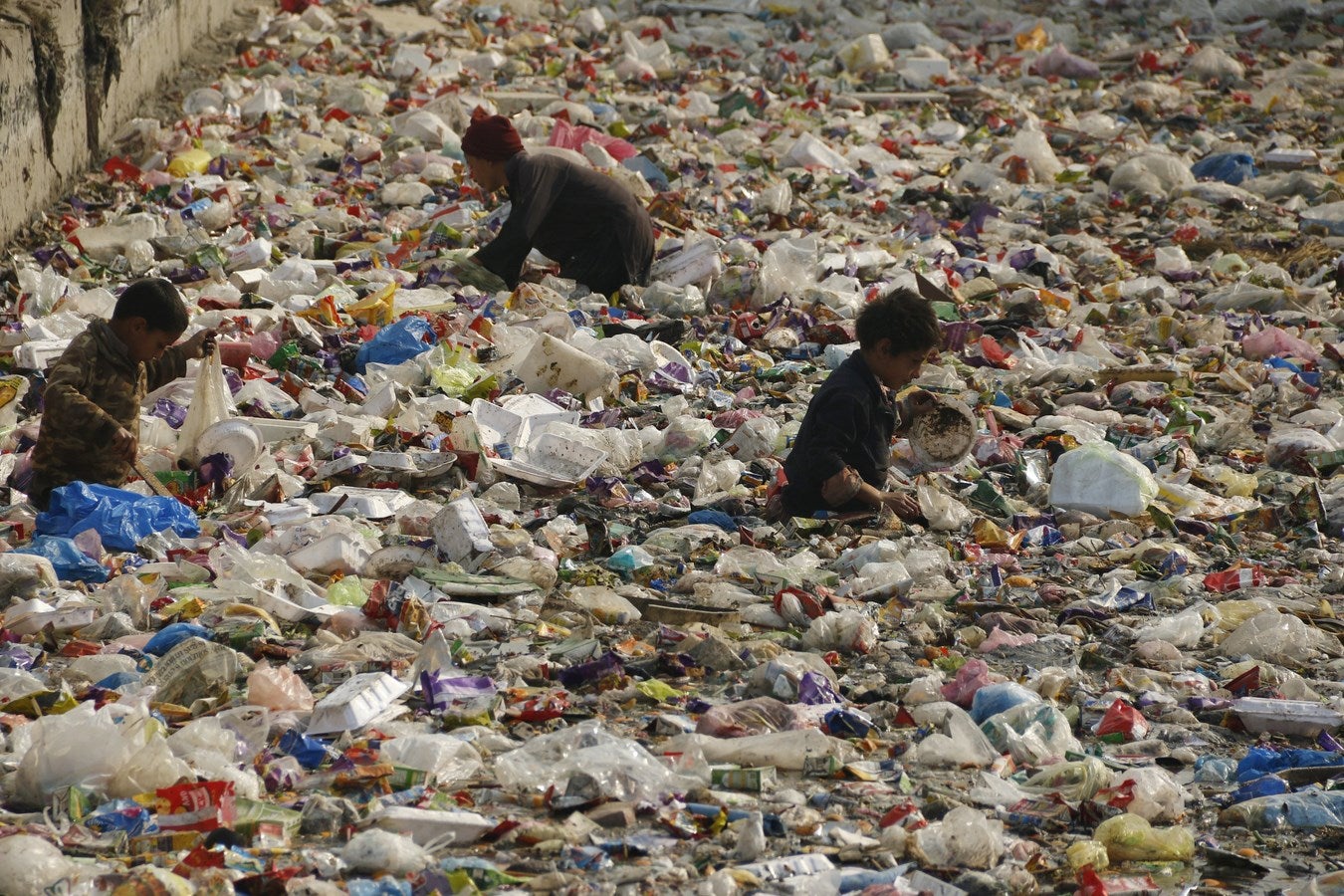 Los niños buscan plástico reciclable en un canal en Peshawar, Pakistán.