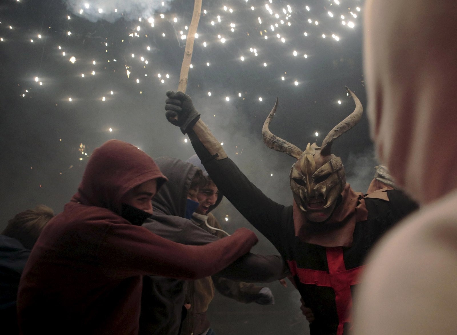Un juerguista vestido como un diablo sostiene un palo con fuegos artificiales durante la tradicional "Correfocs" en las fiestas locales en Palma.