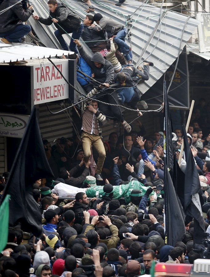 Varios palestinos caen desde un techo de una tienda durante el funeral de siete hombres armados de Hamas que murieron cuando un túnel se derrumbó cerca de la frontera oriental de la Franja de Gaza con Israel en la ciudad de Gaza.