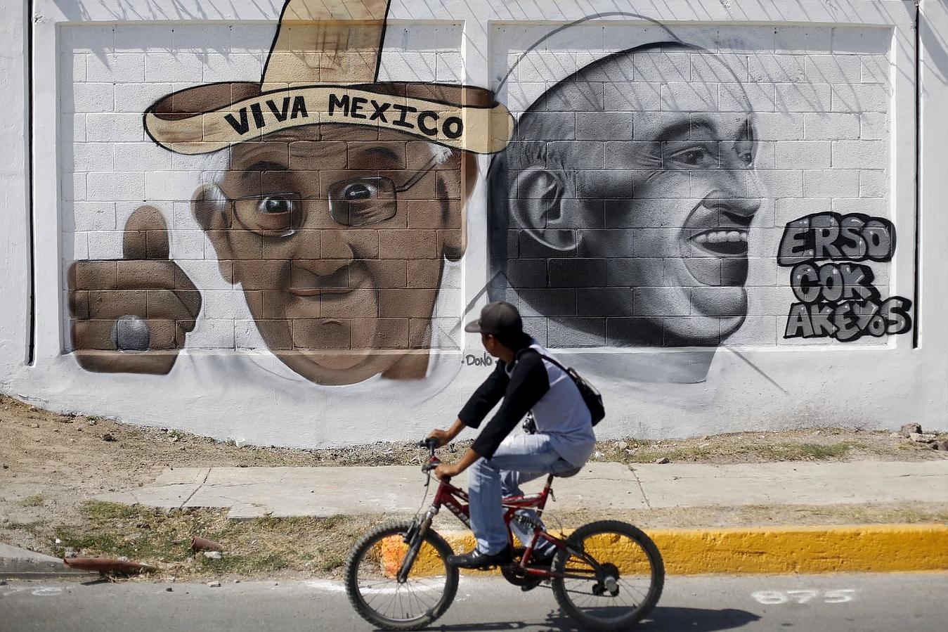 Un hombre sobre su bicicleta delante de una pintada Francisco en Ecatepec, en las afueras de la Ciudad de México.