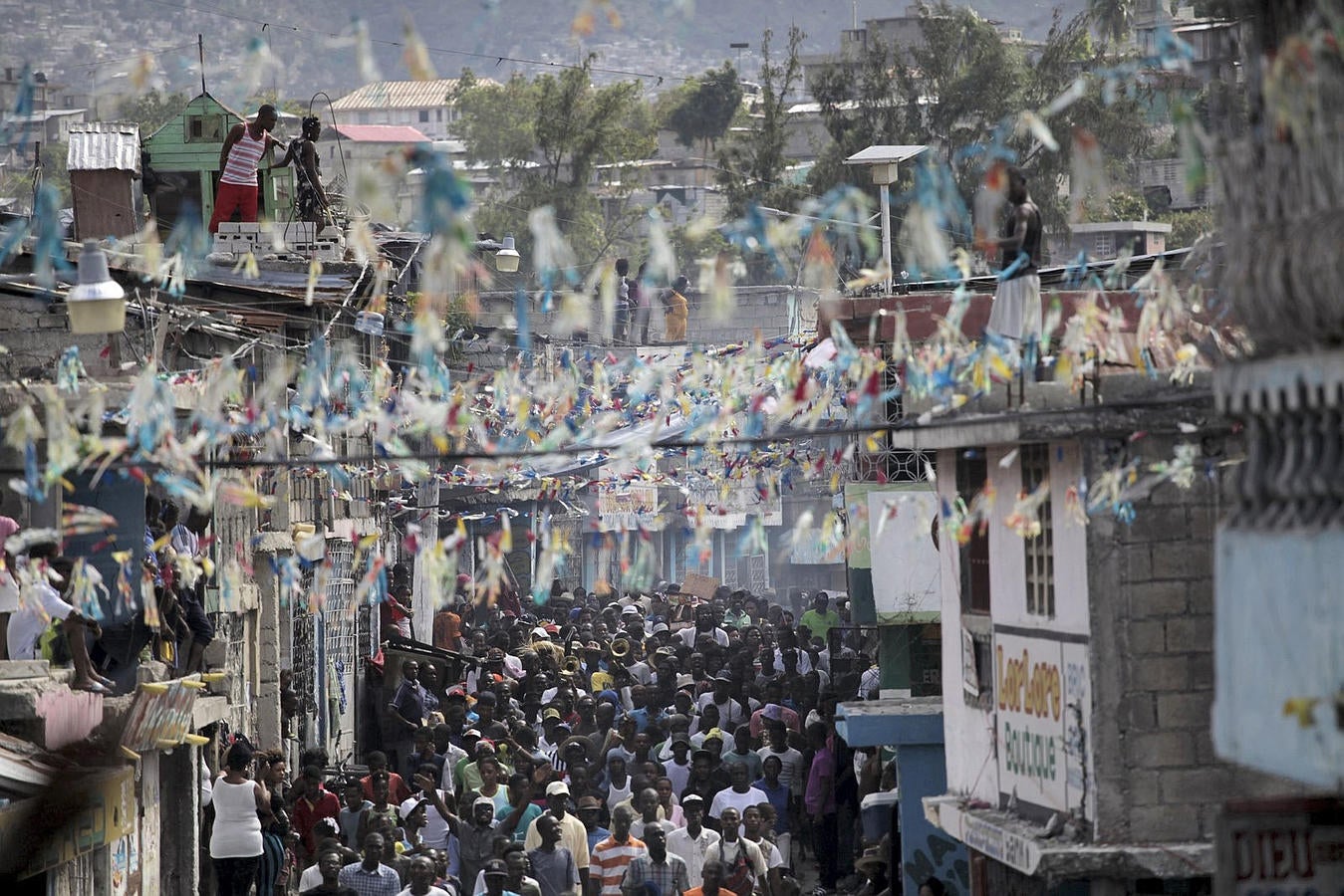 Los residentes miran manifestantes convocados por grupos de oposición, ya que marcha en Port-au-Prince, Haití.