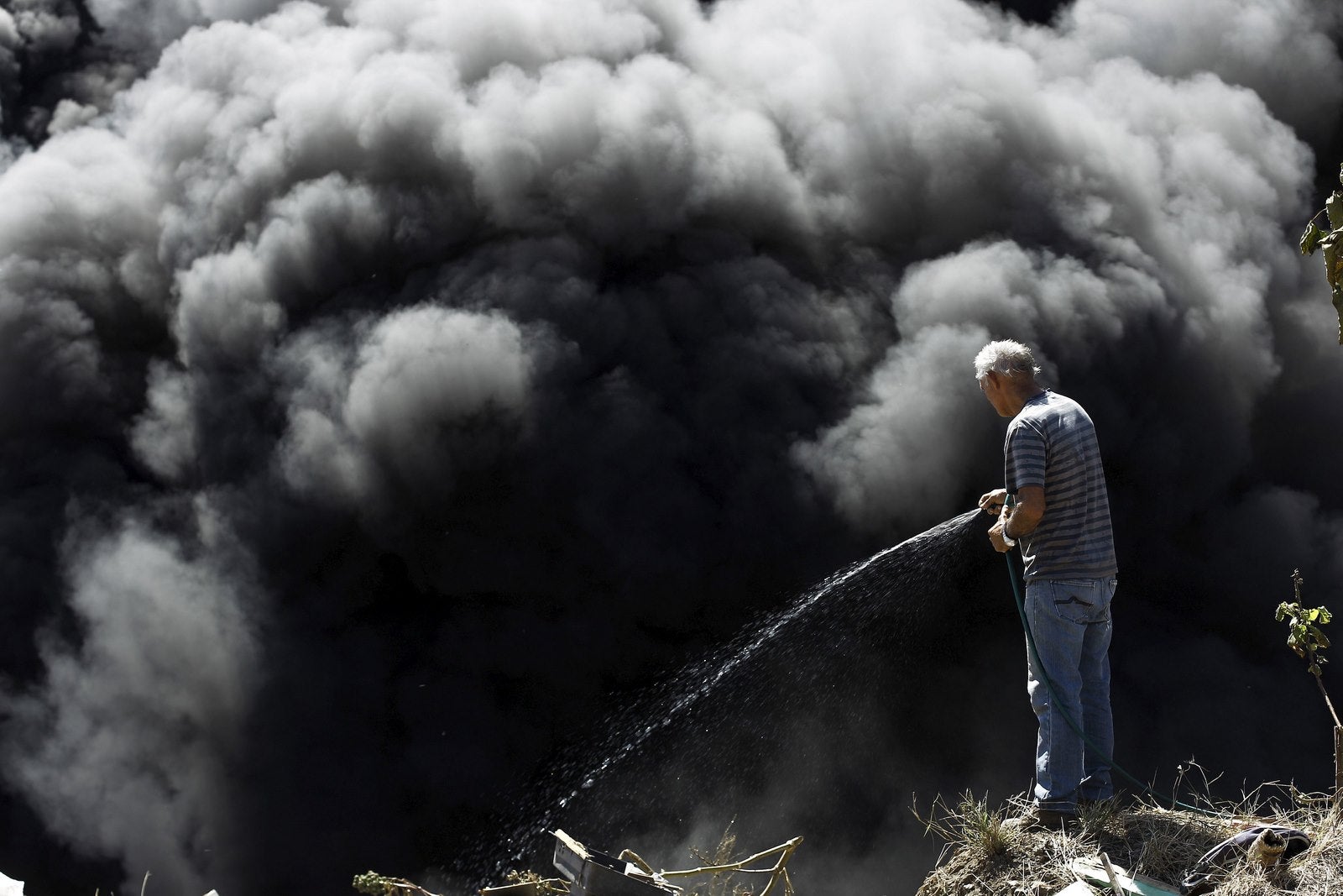 Un hombre intenta extinguir un incendio en un vertedero ilegal, en un barrio pobre de San José, Costa Rica.