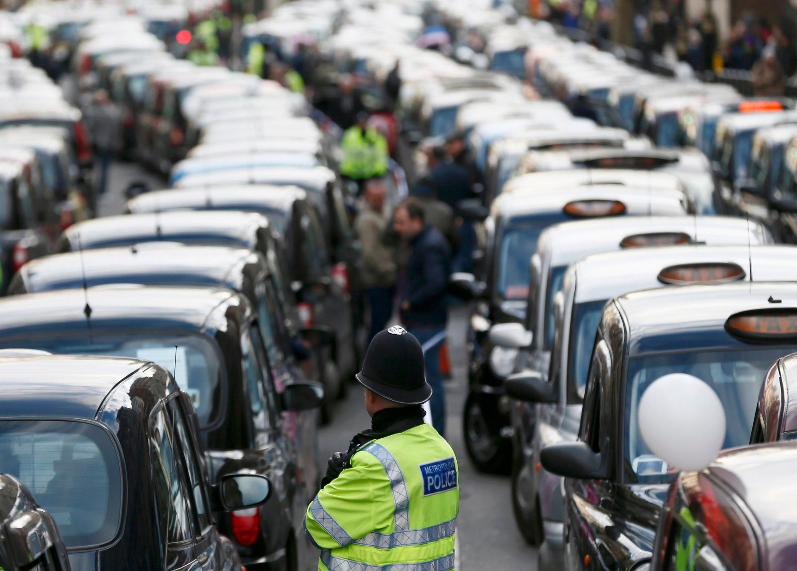 Un oficial de policía se interpone entre filas de taxis durante una protesta de los taxistas de Londres.