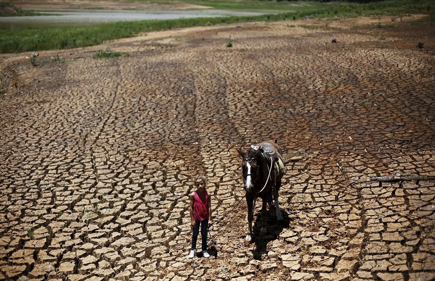 Paula, posa con su caballo en la tierra agrietada de la presa Atibainha, parte del depósito de Cantareira, en Nazare Paulista, cerca de Sao Paulo, Brasil. IMÁGENES