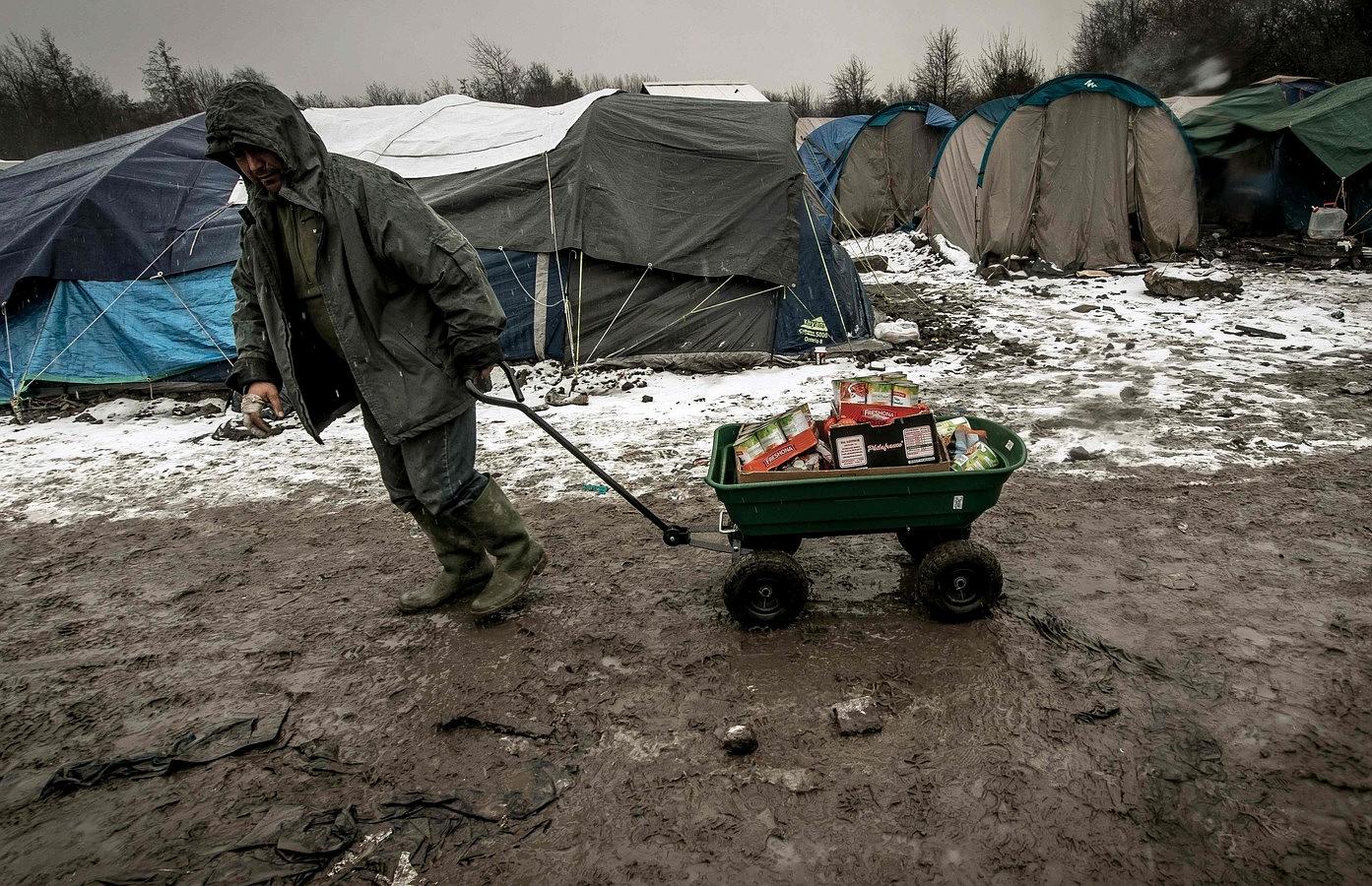 Un hombre lleva el alimento a los refugiados del campo de inmigrantes en Grande-Synthe cerca de Dunkerque, en el norte de Francia, donde 2.500 refugiados de Kurdistán, Irak y Siria viven.