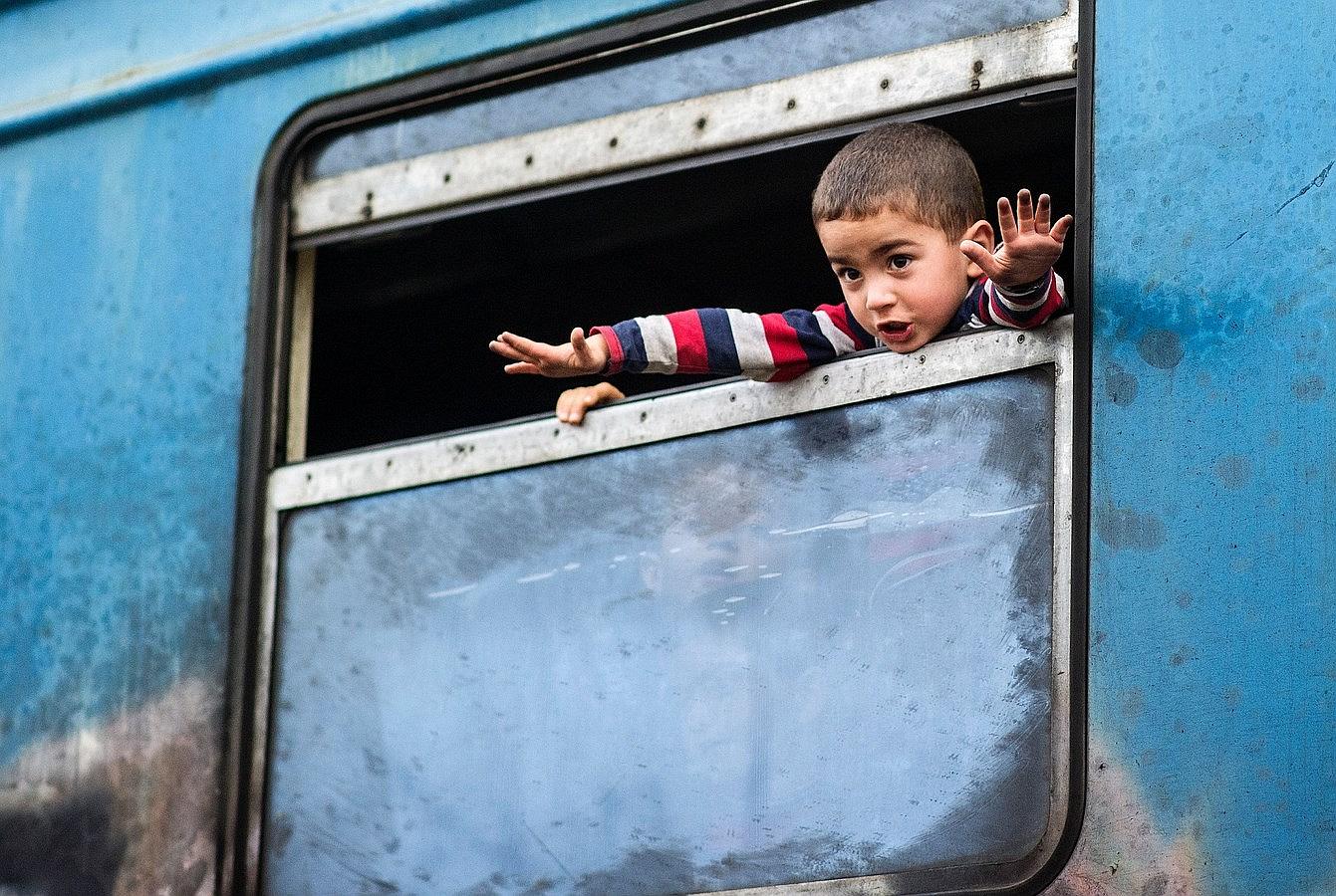 Un niño inmigrante  extiende sus brazos a la espera de un tren en dirección a Serbia desde la frontera con la Macedonia-griega cerca de Gevgelija.