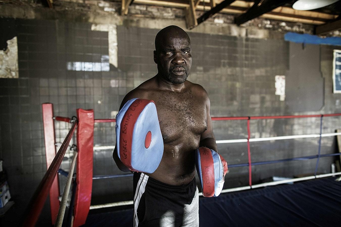 El ex boxeador profesional y entrenador de boxeo George Khosi posa para un retrato en el ring de boxeo, en el club de boxeo Hillbrow en el barrio ruinoso de Hillbrow, en Johannesburgo.