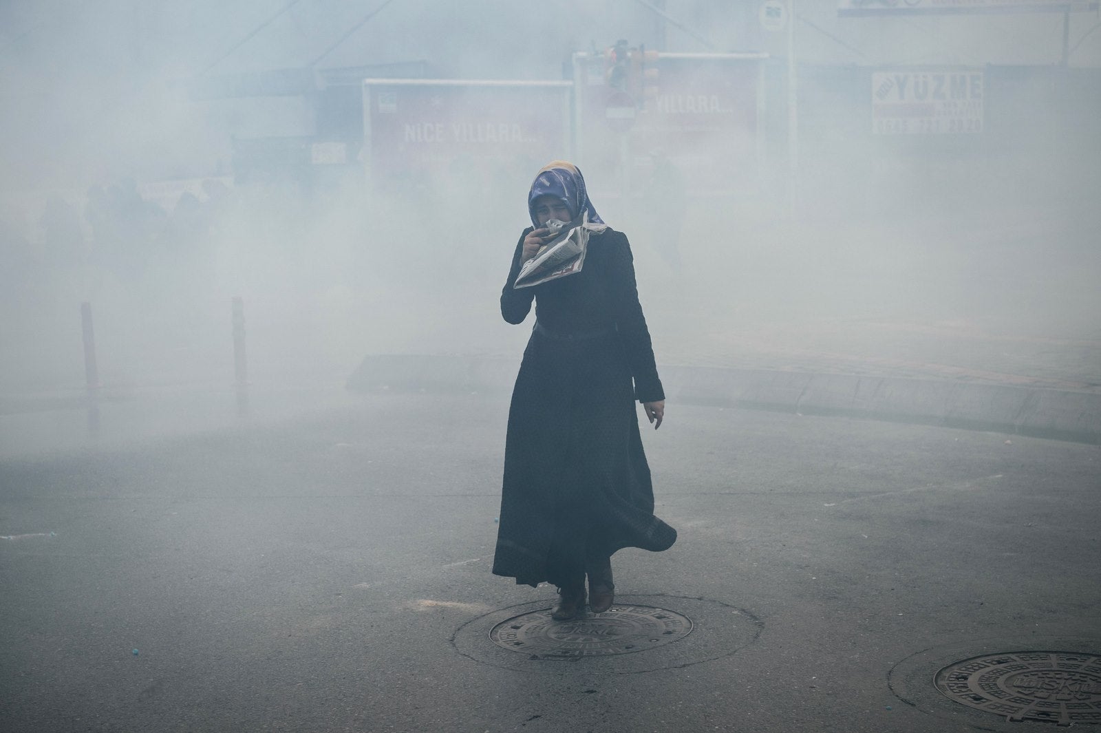 Una mujer se cubre la cara por que agentes de policía antidisturbios turcos usan gases lacrimógenos para dispersar a los seguidores frente a la sede del diario turco Zaman en Estambul.