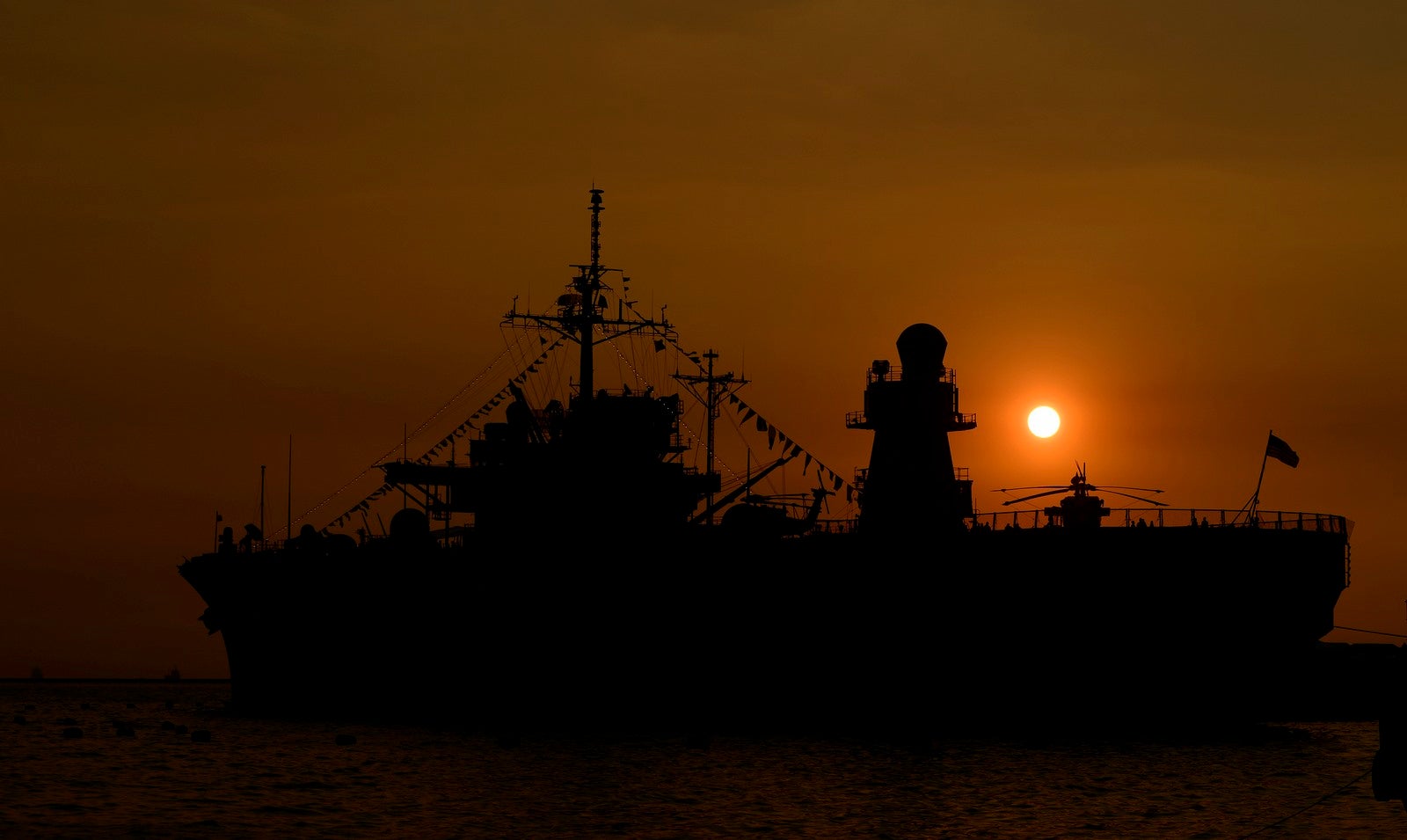 El sol se pone detrás de barco de la marina estadounidense USS Blue Ridge atracado en el muelle de Manila en Manila.