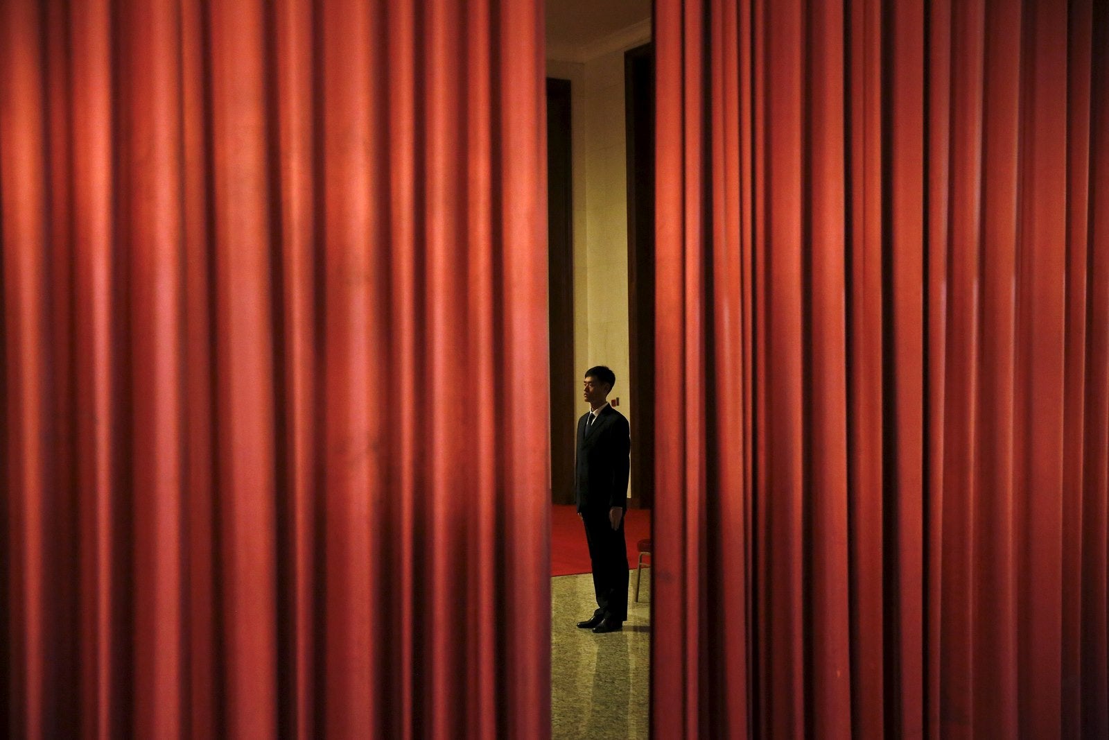 Un agente de seguridad vigila la zona desde detrás de las cortinas en el interior del Gran Palacio del Pueblo, en Beijing, China